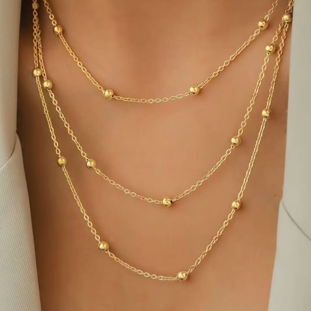 Collier trois rangs de perles dorées porté