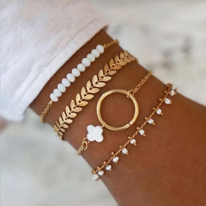 Lot de bracelets dorés et perles blanches au poignet